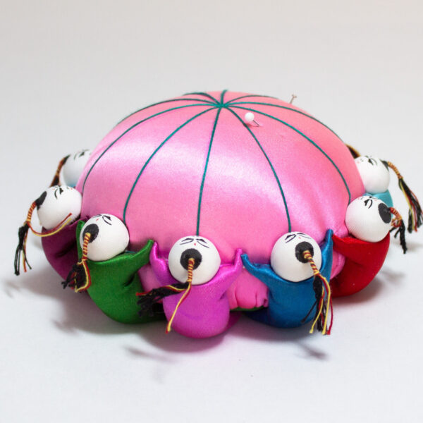 Pink Satin Pin Cushion With 10 Colorful Dolls Holding Hands